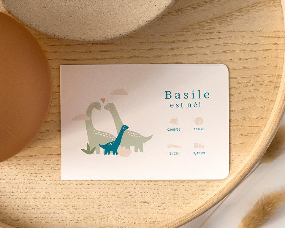 Faire-part de naissance avec 3 dinosaures, deux verts qui désignent les parents et un petit bleu qui désigne l'enfant.