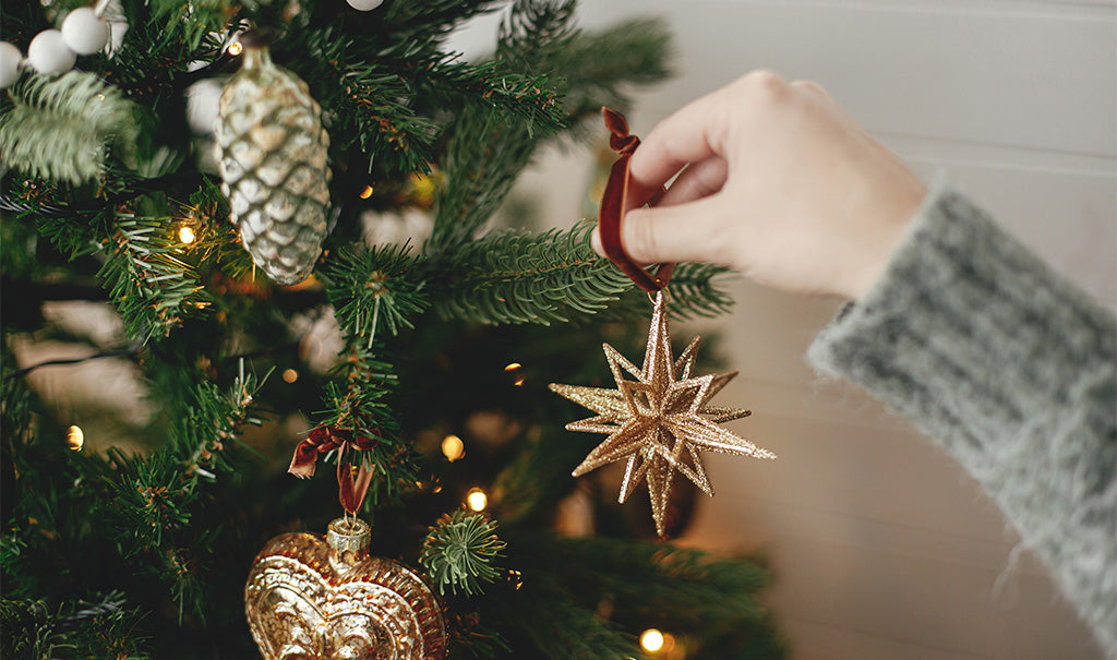 Une main accroche une décoration de noël en forme d'étoile sur son sapin