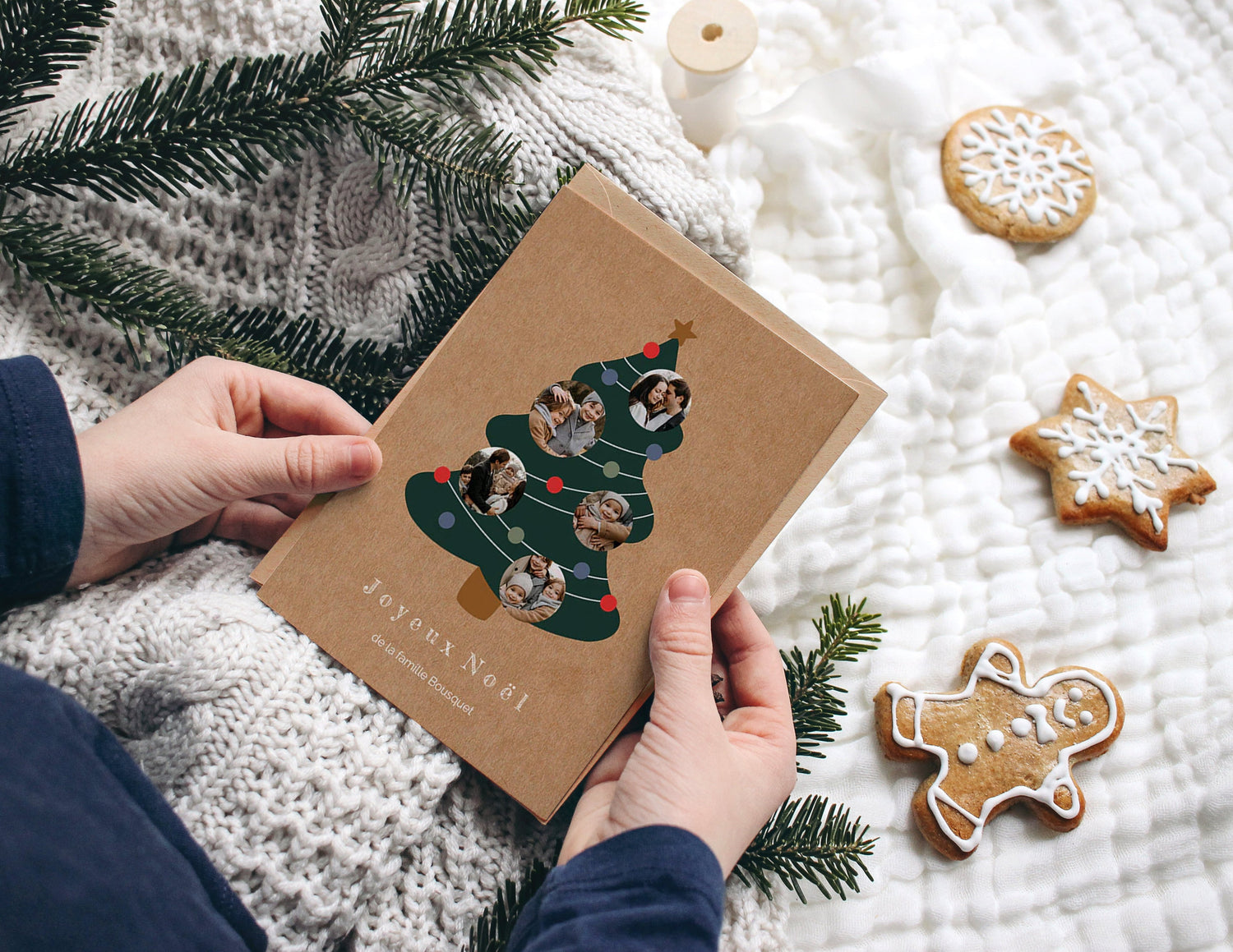 Mains qui tiennent une carte de noël personnalisable avec un sapin de noël et des photos de famille dessus.