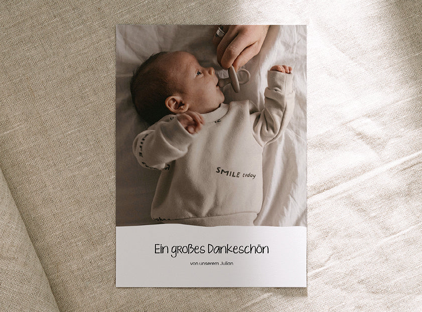 Einfache Dankeskarte zur Geburt im Hochformat mit einem Babyfoto und dem Text „Ein großes Dankeschön“.